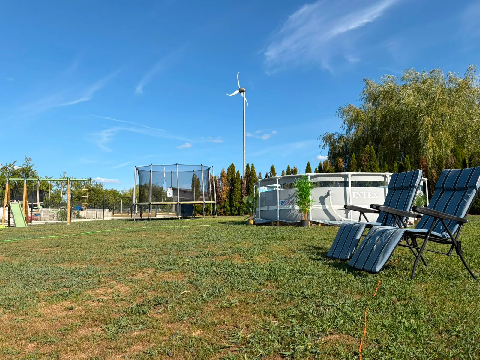 Le grand jardin clôturé : transats, piscine et trampoline sous le ciel d’été