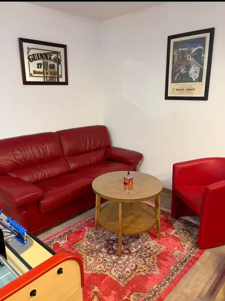 Le salon du pub : canapé en cuir rouge sous le miroir Guinness