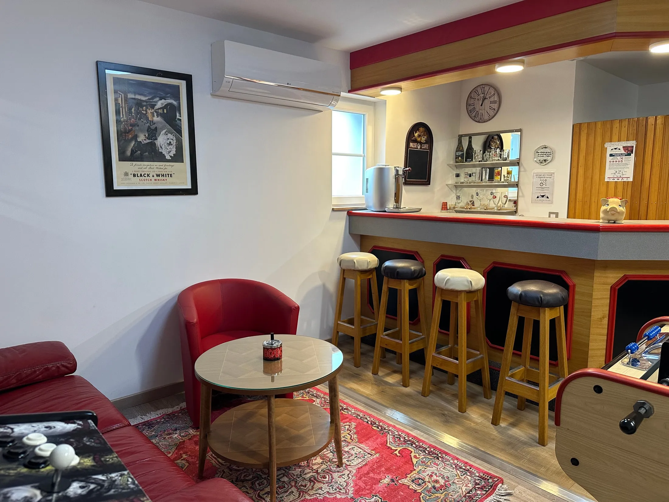 Le comptoir du bar, ses tabourets et le fauteuil club en cuir rouge