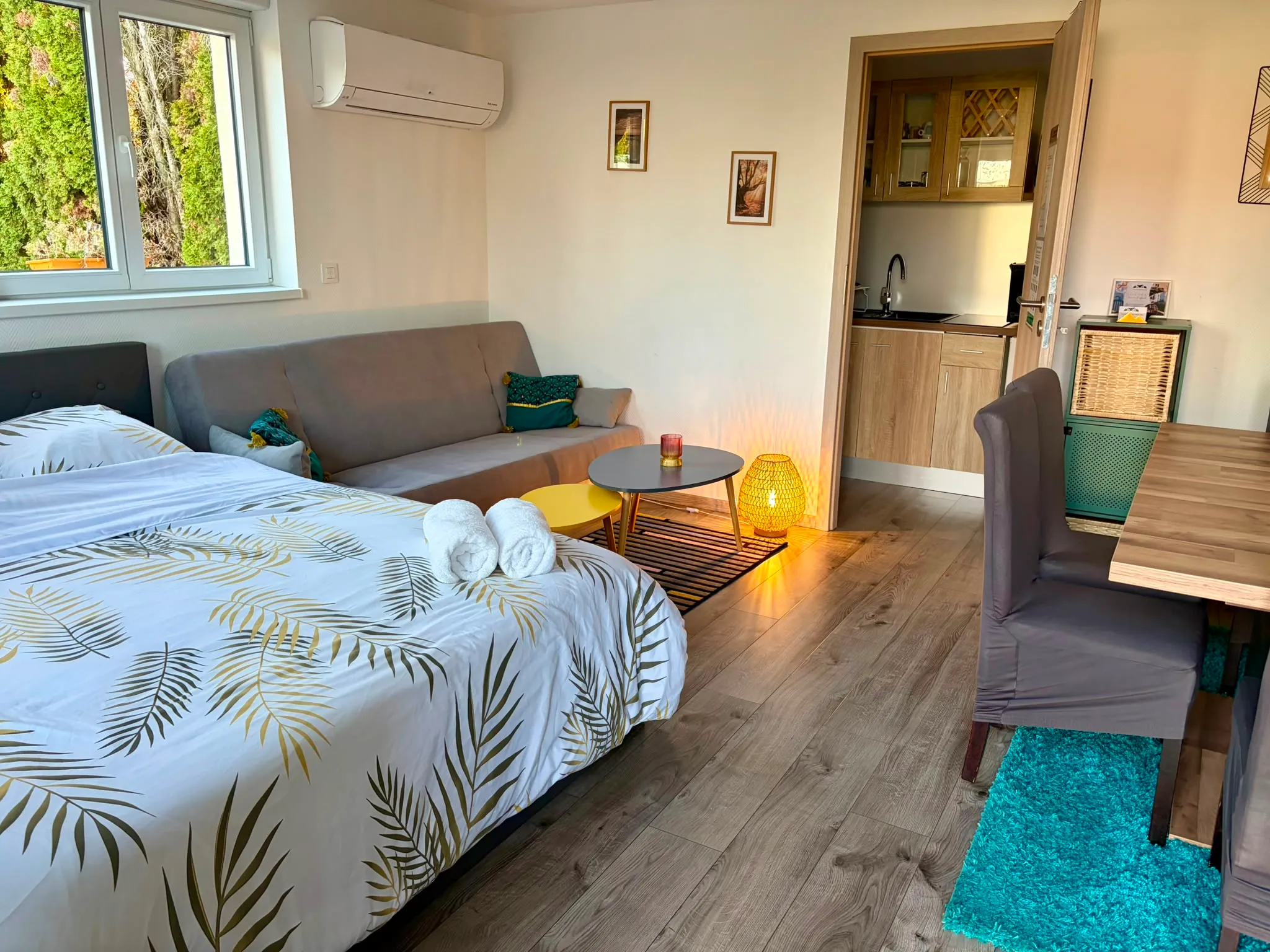 Le studio de la Petite Escale : lit, canapé, lampe allumée et kitchenette