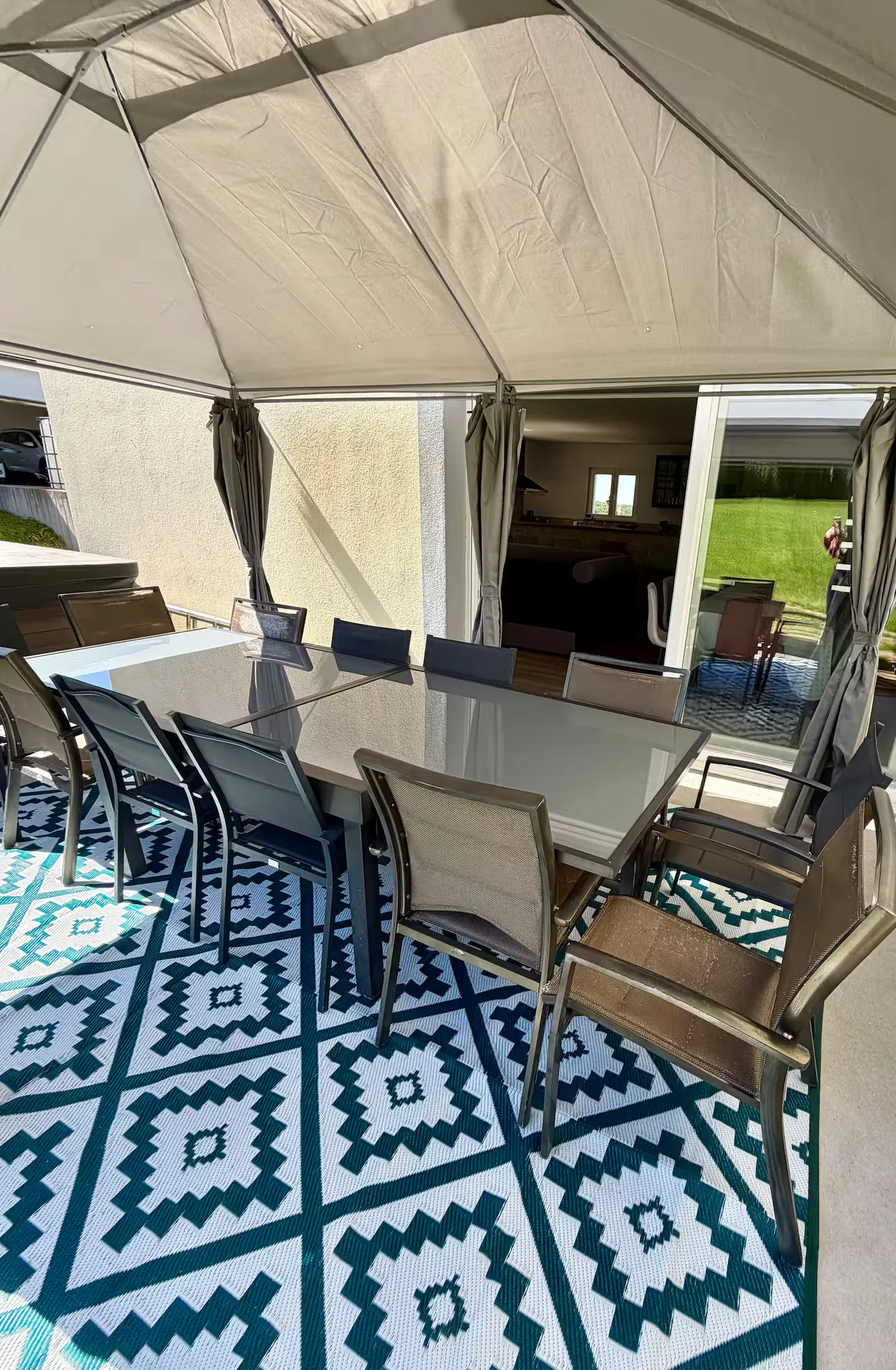 La pergola ouverte sur le séjour, la grande table dressée sous la toile